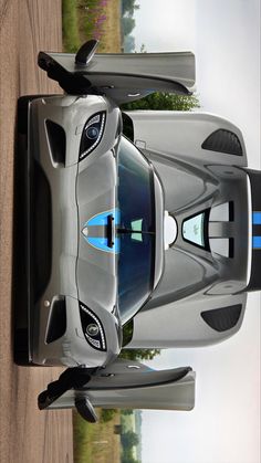 a silver sports car parked on top of a grass covered field