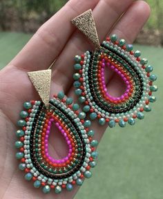 a pair of colorful beaded earrings is held in someone's hand