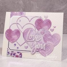 a card with hearts and the words love you written in white letters on purple paper