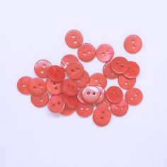 a pile of red buttons sitting on top of a white table