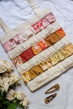 a white bag sitting on top of a table next to some flowers and hair clips