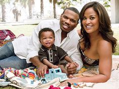 a man and woman laying on the grass with a baby in front of them holding a toy house