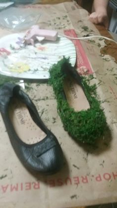 two pairs of shoes sitting on top of a table covered in green grass next to a paper plate