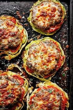 four spaghetti dishes on a baking sheet ready to go in the oven, with cheese and sauce