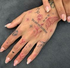 a woman's hand with tattoos on it and flowers in the middle of her left hand