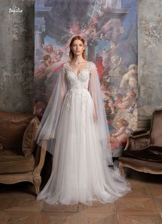 a woman standing in front of a painting wearing a white wedding dress with long sleeves