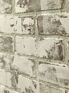 an old brick wall with peeling paint and chippings on the bricks is shown