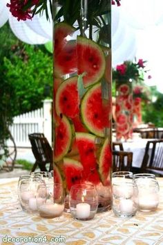 there is a vase with watermelon slices in it and candles on the table