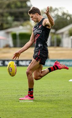 a man kicking a soccer ball on top of a field