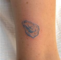 a small tattoo on the arm of a person with a blue inked shell in it