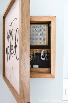 a wall mounted jewelry box with the words get naked on it and various necklaces