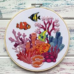 an embroidery project with fish and corals on white wooden background, close up view