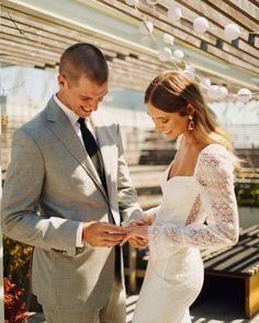 a bride and groom standing under an awning holding each other's wedding rings