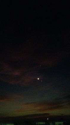 an airplane flying in the sky at night with a bright moon behind it and some clouds