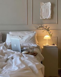 a laptop computer sitting on top of a white bed