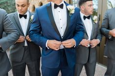 a group of men in tuxedos standing next to each other and adjusting their ties