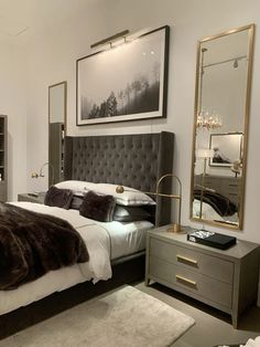 a bedroom with a bed, dresser and mirror in the corner is decorated in white and grey tones