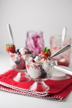 two glasses filled with dessert sitting on top of a checkered tablecloth covered table