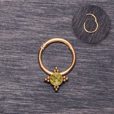 a gold nose ring with a green stone in the middle and an earring attached to it