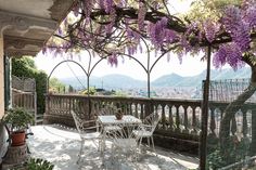 an outdoor dining area with wistery vines on the roof and balcony railings