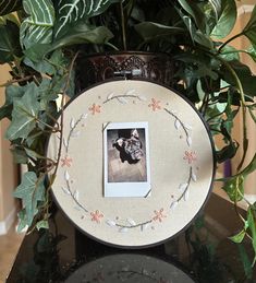 a photo frame sitting on top of a black table next to a potted plant