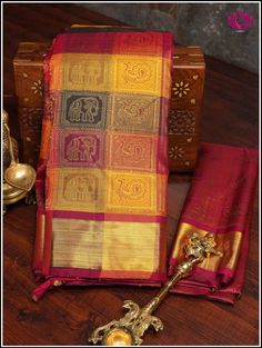 Epitome of luxury and grace, this Kanchipuram silk saree in a stunning color combination is just enough to steal any ocassion. Checkered patterned body in tones of red, yellow and dark green with gold zari woven elpehant and peacock motifs and zari woven border makes it a perfect showstopper for special occasion . Rich pallu adds grandeur. It comes with an unstitched plain blouse. Silk mark certified. Handloom saree. Handmade tassels. Edging done on the other side. Blouse - Unstitched. Please no Multicolor Saree With Temple Jewelry In Traditional Drape, Multicolor Saree With Temple Jewelry Style, Designer Saree With Zari Weaving, Designer Red Tussar Silk Saree, Red Tussar Silk Saree With Motifs, Red Tissue Silk Saree For Traditional Ceremonies, Designer Traditional Wear With Pallu For Ceremonies, Elegant Red Handloom Saree, Red Tussar Silk Saree