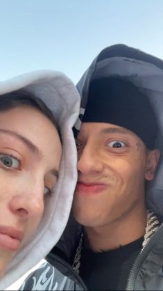 a young man and woman are posing for a photo with the sky in the background