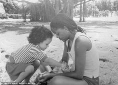 a black and white photo of a woman with a young child on the ground outside