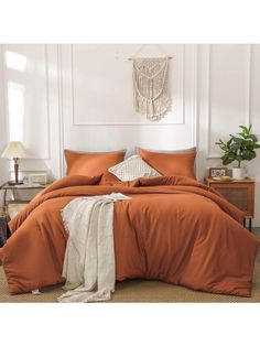 an orange comforter set in a bedroom with white walls and brown carpeted flooring