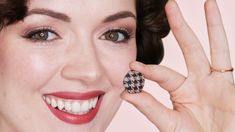 a close up of a person holding a ring in front of her face and smiling