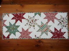 a quilted placemat with red and green stars on it sitting on a wooden floor