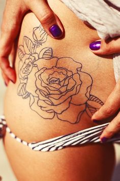 a close up of a person's stomach with tattoos on her belly and flowers