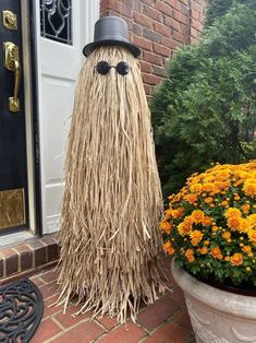 a scarecrow is standing next to a potted plant