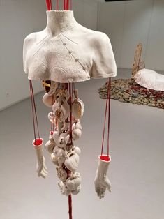 a white sculpture with red strings hanging from it's sides