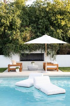 two lounge chairs and an umbrella by the pool