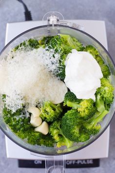 broccoli and other vegetables in a food processor with some white stuff on top