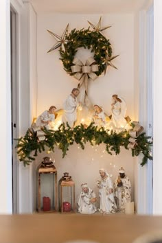 christmas decorations on the mantle in front of a wreath with angels and starbursts