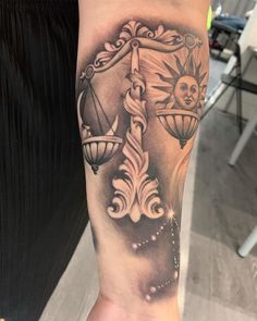 a person with a tattoo on their arm holding a clock and hourglass in front of them