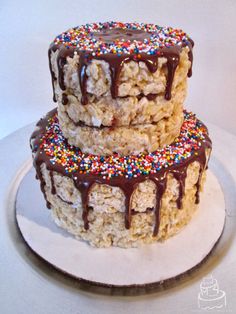 two cakes with chocolate frosting and sprinkles stacked on top of each other