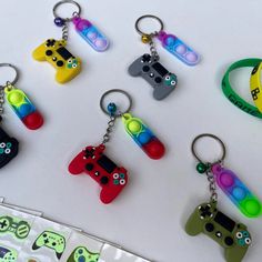 six different colored video game controllers keychains on a white table with stickers