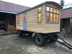 a small wooden house sitting on the back of a truck in front of a building