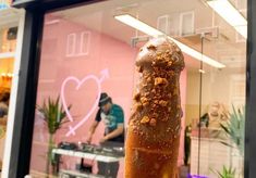 an ice cream sundae on a stick in front of a store window with people working behind it