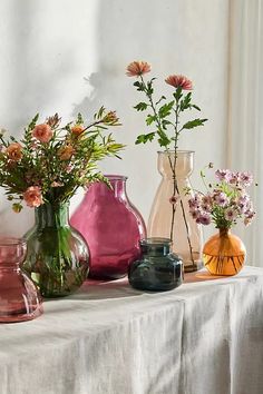 there are many vases with flowers in them on the table next to each other