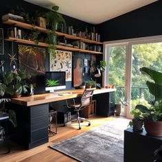 a home office with plants and pictures on the wall, along with a large window