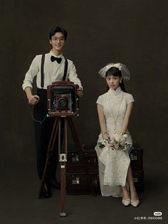 a man and woman standing next to each other in front of an old fashioned camera