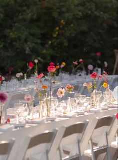 the tables are set up with clear vases and flower centerpieces on them