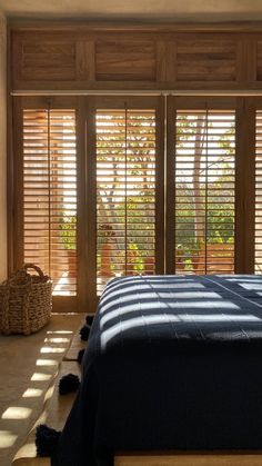 a bed sitting in a bedroom next to wooden shutters