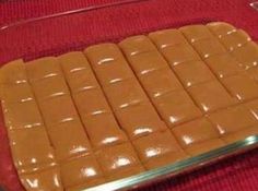 a glass dish filled with chocolate squares on top of a red table cloth and silver serving utensils