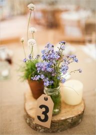 a wooden table topped with a vase filled with blue flowers and a number on it