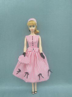 a doll wearing a red and white striped dress with black gloves on it's head